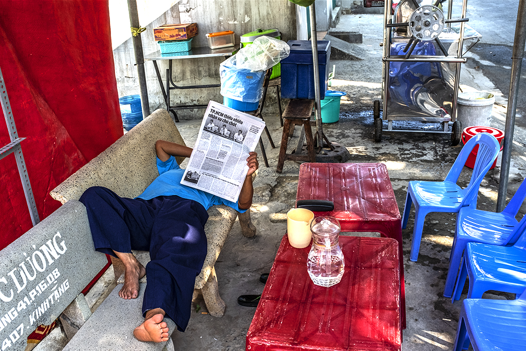 Sugarcane juice man reading a newspaper--Saigon