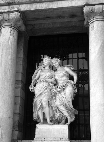 A statue of two goddesses made out of a white marble at the Palacio of Bellas Artes in Mexico City