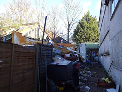 A view from further back showing both of the two previously-pictured buildings.  Even more debris is visible here, as well as a moped with a broken numberplate.