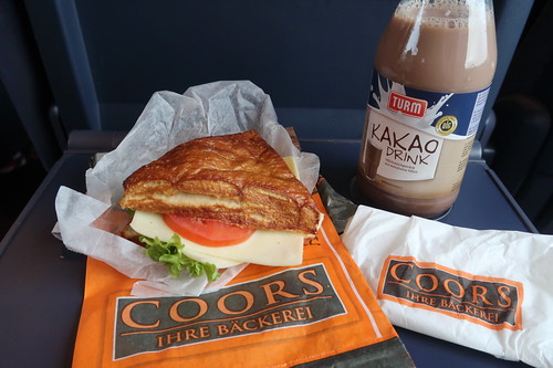 Vegetarisch belegte Laugenecke von der Bäckerei Coors (Osnabrück Hbf) mit Kakao Drink als Frühstück auf Zugfahrt nach Passau