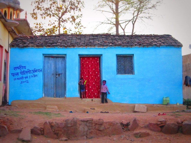 Two Indian boys play Holi outside their blue house in Orchha